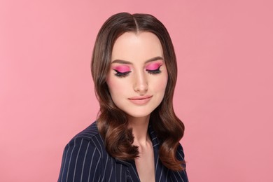 Photo of Portrait of beautiful young woman with makeup and gorgeous hair styling on pink background
