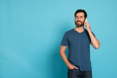 Photo of Happy man talking on phone against light blue background. Space for text