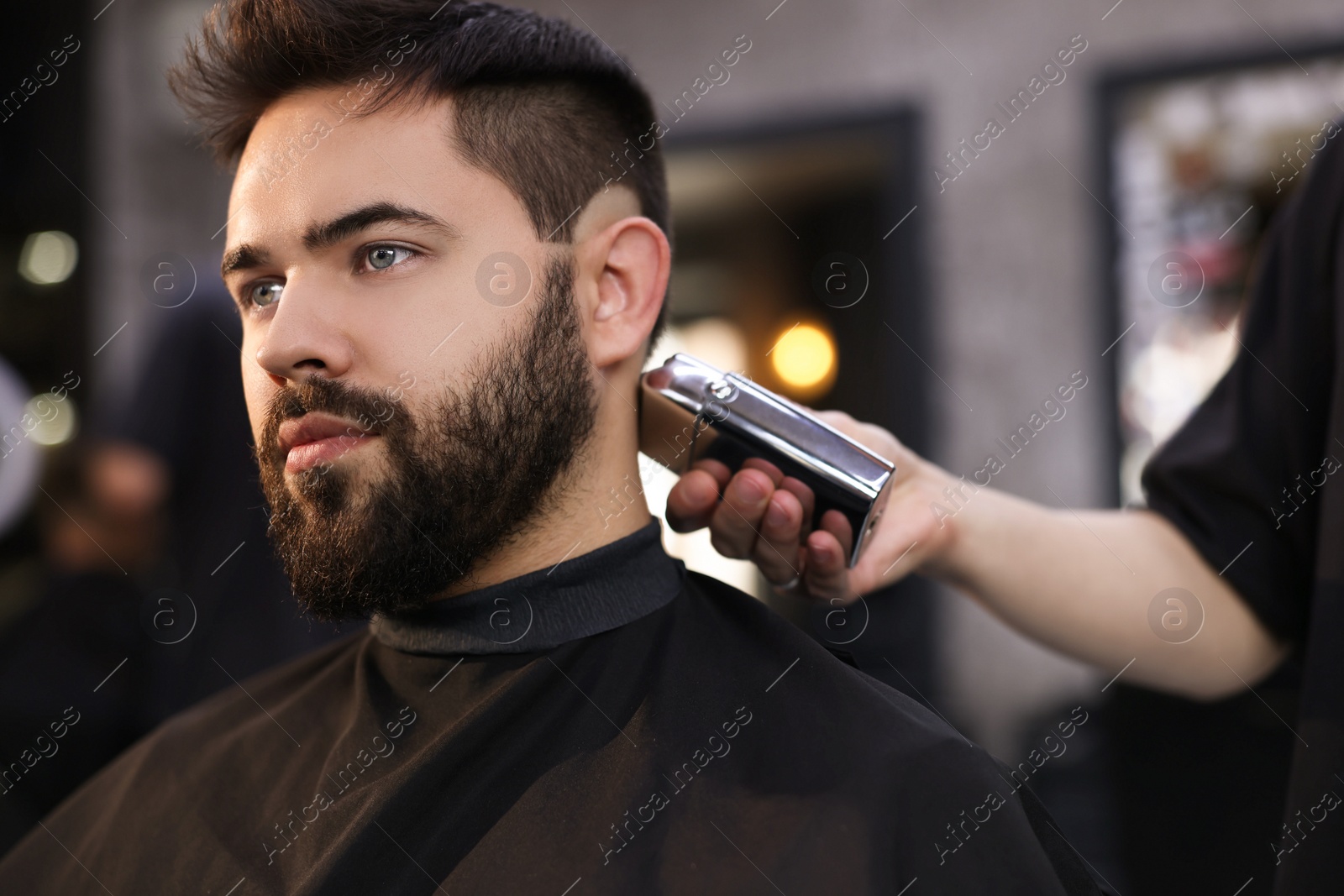 Photo of Professional hairdresser working with client in barbershop