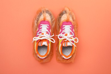 Women's sneakers in shoe covers on coral background, top view