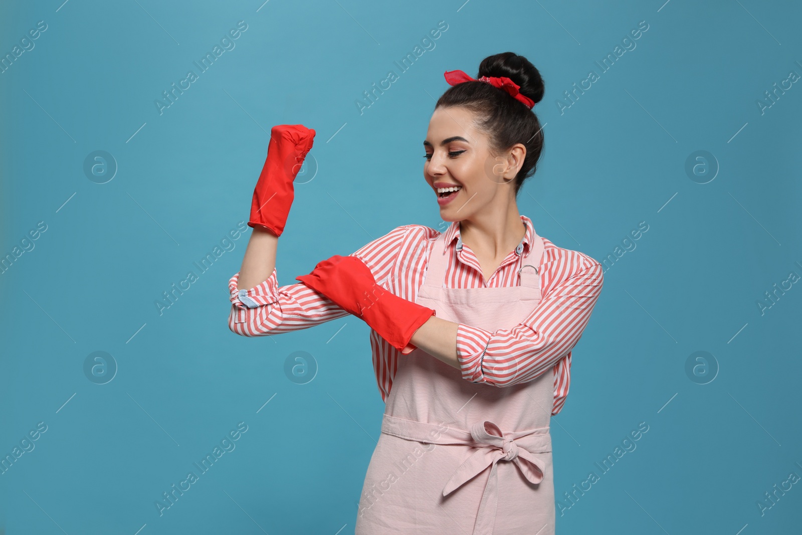 Photo of Housewife wearing rubber gloves on light blue background