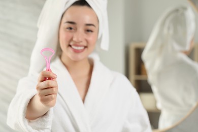 Photo of Happy woman with tongue cleaner in bathroom, selective focus