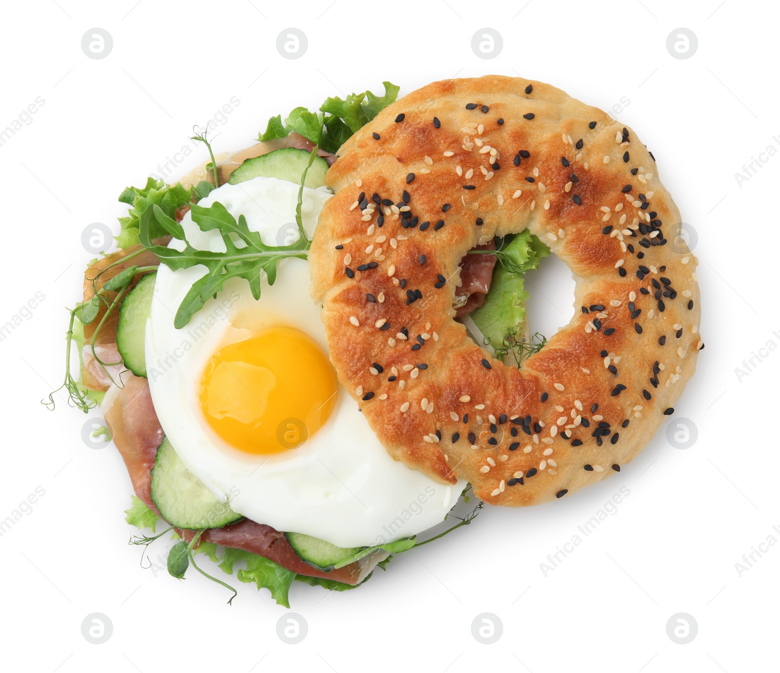 Photo of Tasty bagel with cured ham, egg, cucumber and salad mix isolated on white, top view