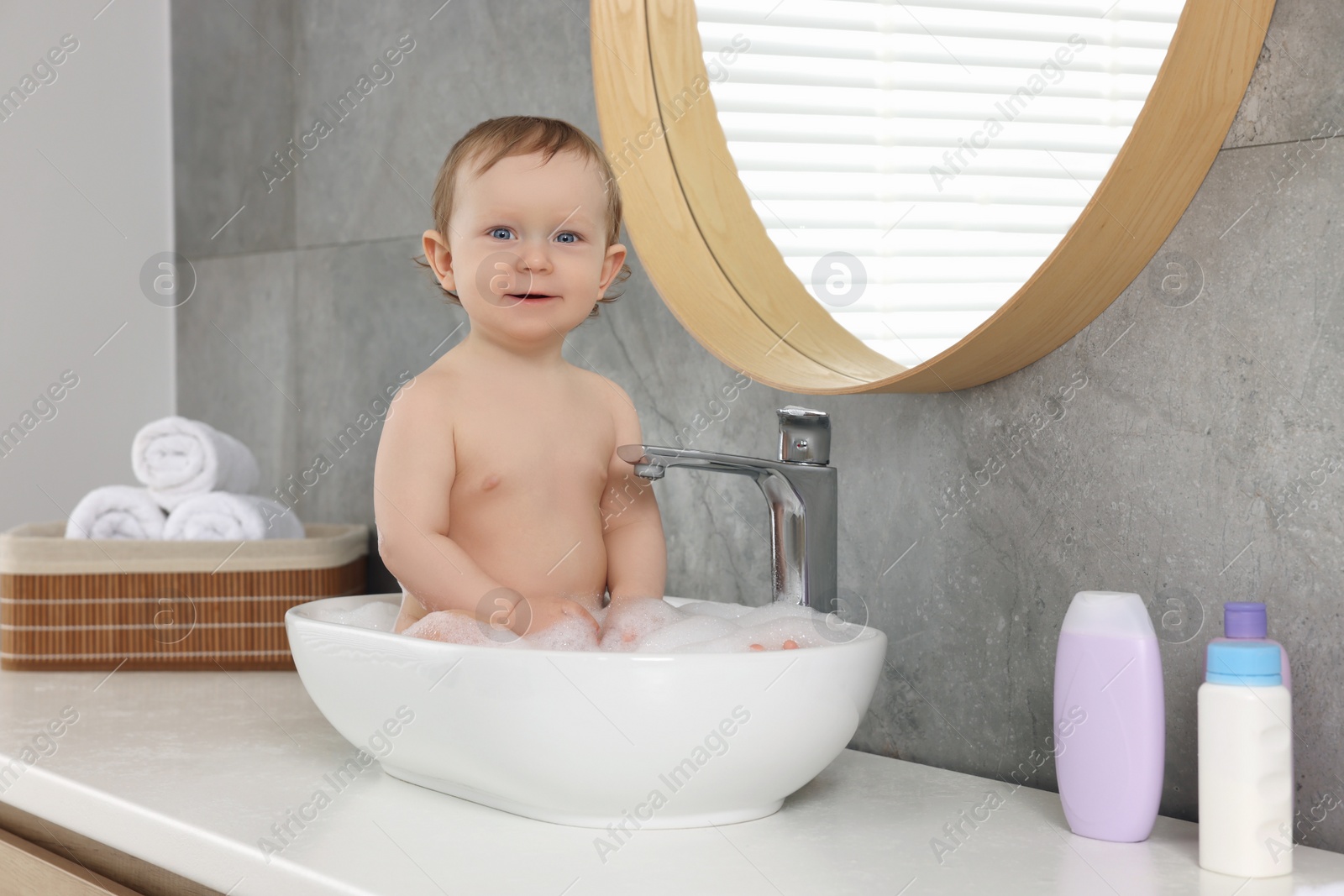 Photo of Cute little baby bathing in sink at home