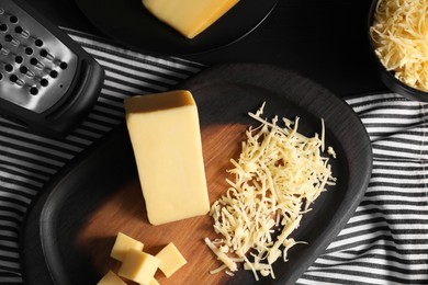 Photo of Grated, cut cheese and grater on table, flat lay