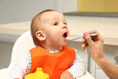 Young mother feeding her little baby at home