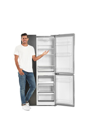 Man near open empty refrigerator on white background