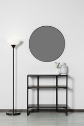 Photo of Stylish round mirror on white wall over table in room