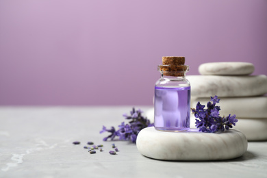 Stones, bottle of essential oil and lavender flowers on marble table. Space for text