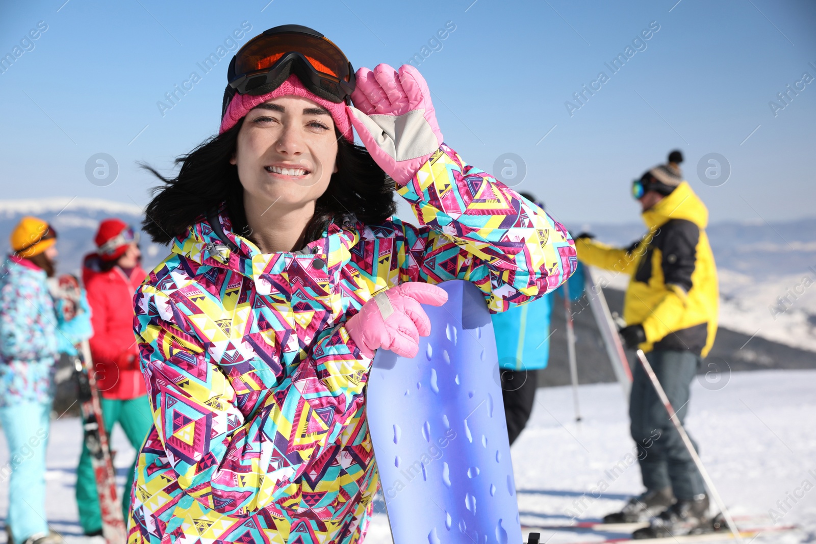 Photo of Young woman with snowboard at ski resort. Winter vacation