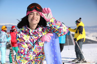 Young woman with snowboard at ski resort. Winter vacation