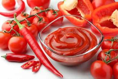 Photo of Bowl of tasty ketchup, tomatoes and peppers on white table, closeup