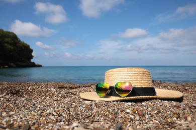 Photo of Straw hat and colorful heart shaped sunglasses on sea beach. Space for text