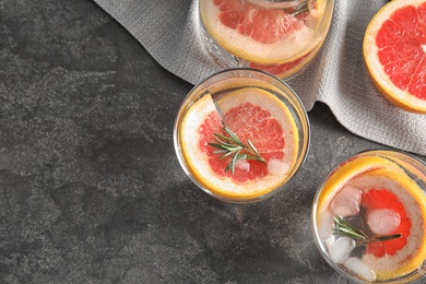 Photo of Glasses of infused water with grapefruit slices on grey table, flat lay. Space for text