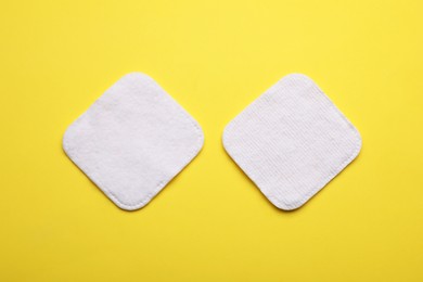 Photo of Soft clean cotton pads on yellow background, flat lay
