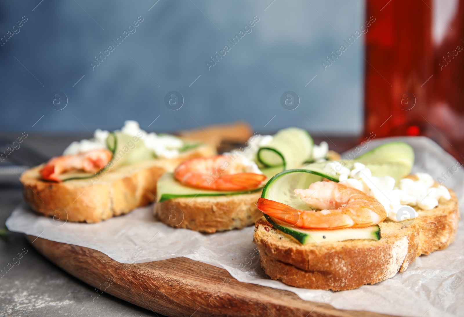 Photo of Cutting board of delicious bruschettas with shrimps on grey table