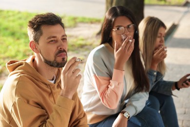 Photo of People smoking cigarettes outdoors on sunny day