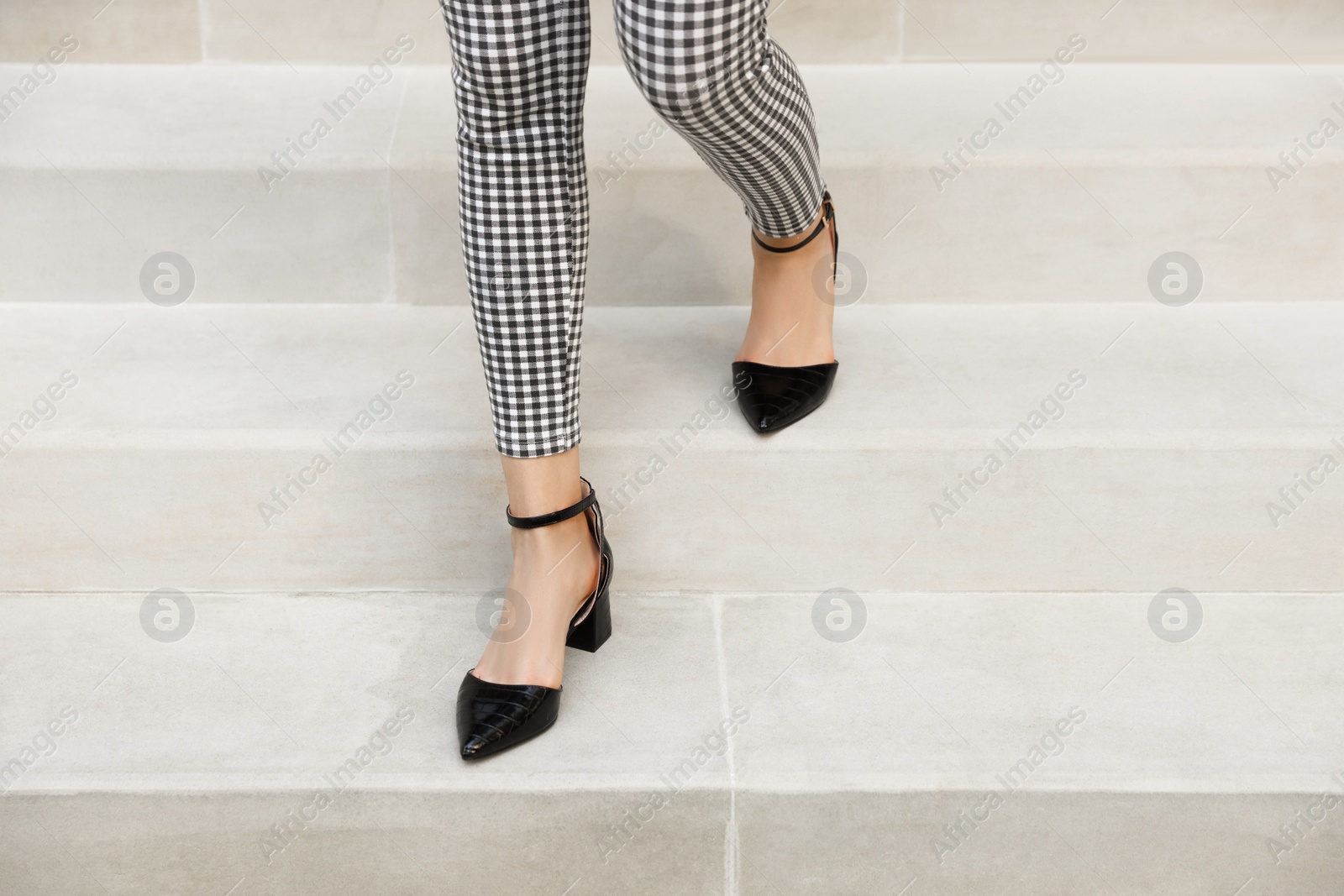 Photo of Woman in stylish black shoes walking down stairs, closeup