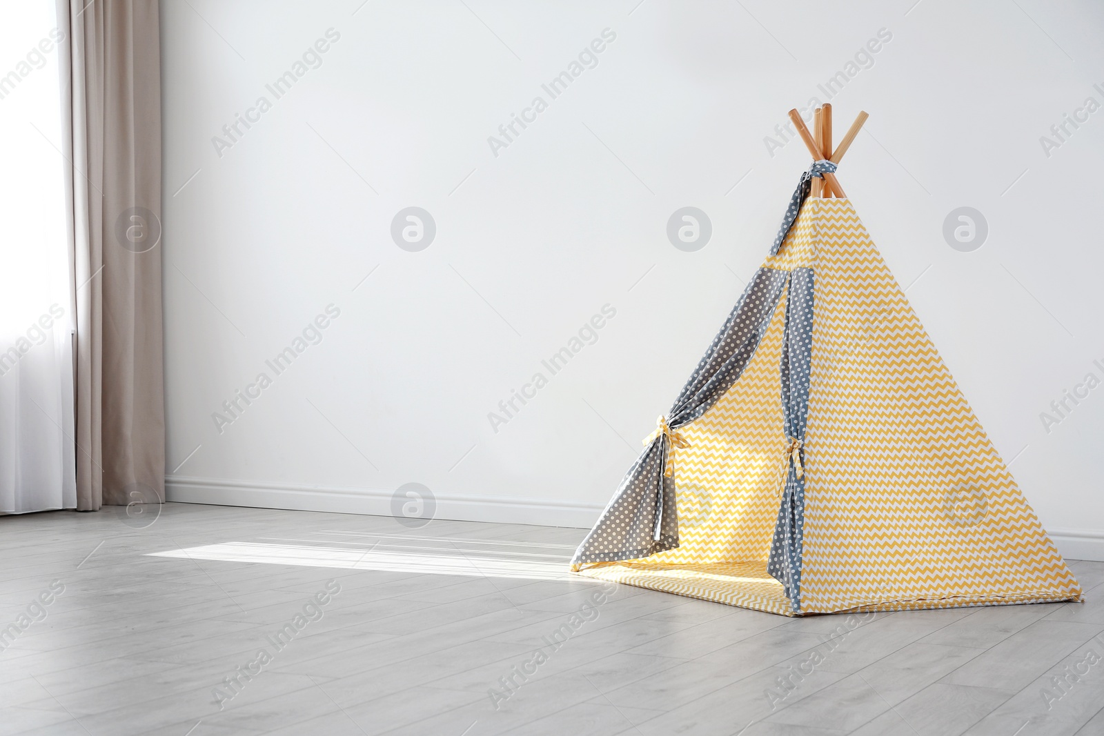 Photo of Cozy play tent for kids as element of nursery interior in empty room with space for text