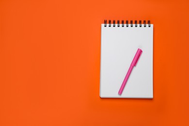 Photo of Blank office notebook and pen on orange background, top view. Space for text
