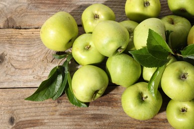 Many fresh apples and leaves on wooden table, top view