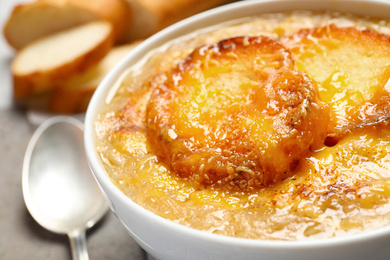 Photo of Tasty homemade french onion soup served in ceramic bowl, closeup