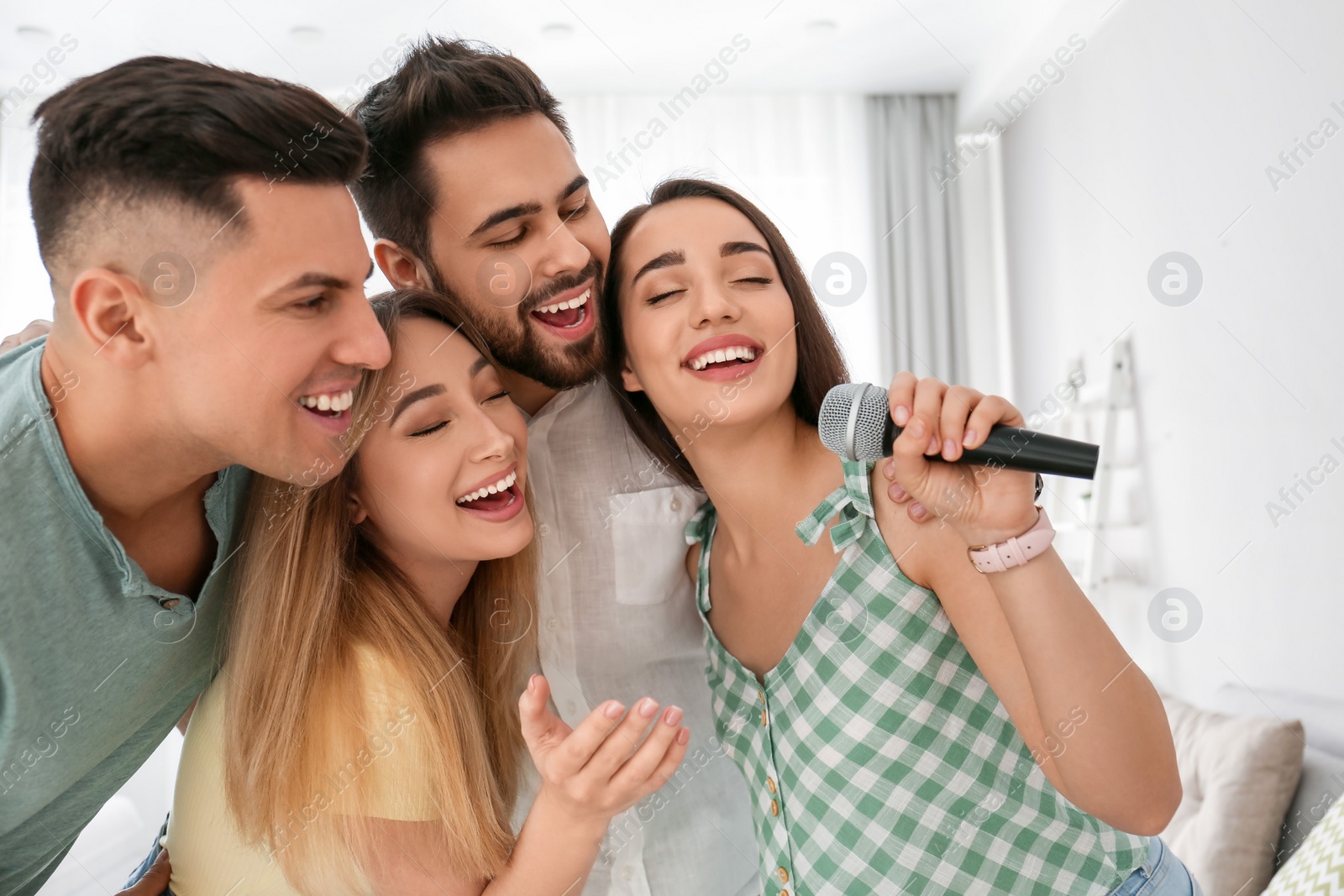 Photo of Happy friends singing karaoke together at home