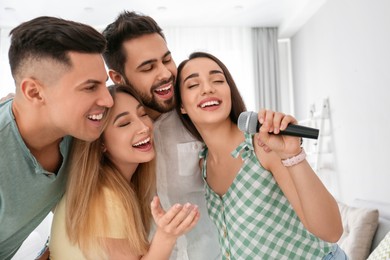 Happy friends singing karaoke together at home