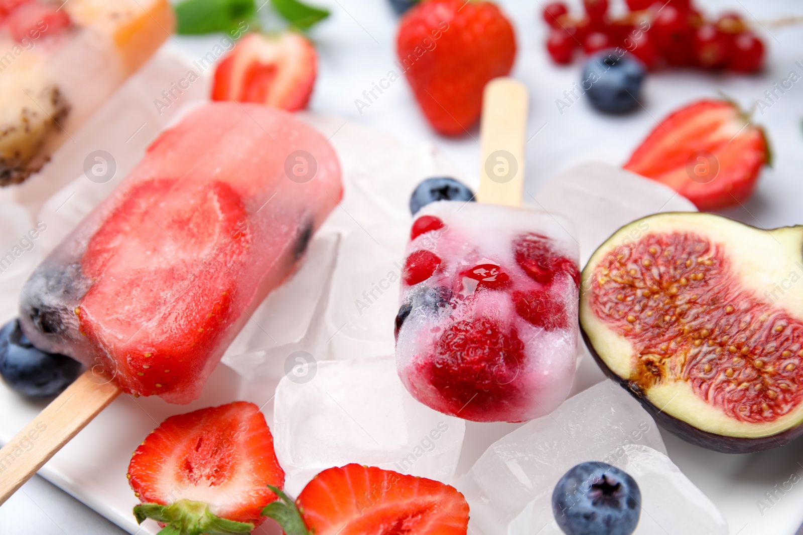 Photo of Tasty refreshing fruit and berry ice pops on light table, closeup