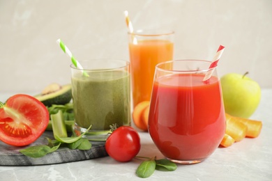 Photo of Delicious vegetable juices and fresh ingredients on light grey table