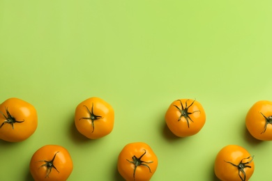 Photo of Yellow tomatoes on green background, flat lay. Space for text