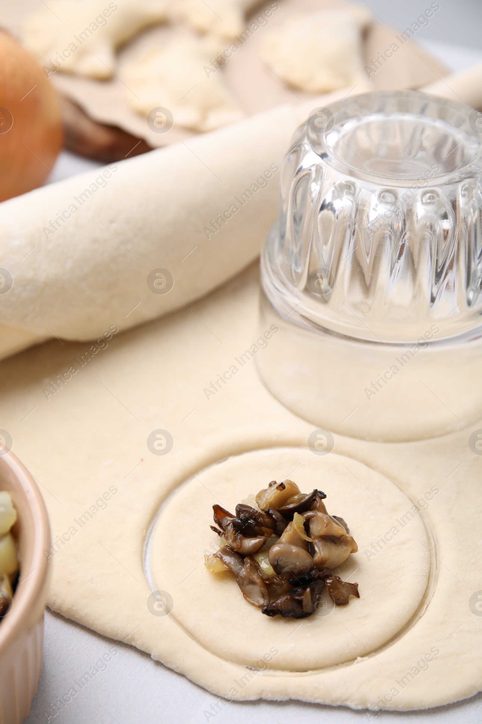 Photo of Process of making dumplings (varenyky) with mushrooms. Raw dough and ingredients on white table, closeup