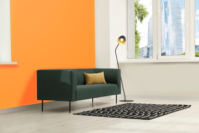 Photo of Beautiful interior with sofa and floor lamp near orange wall