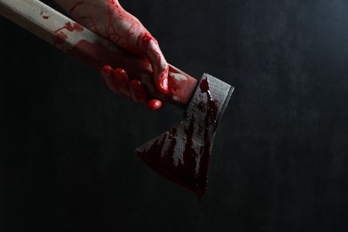 Photo of Man holding bloody axe on dark gray background, closeup