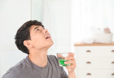 Photo of Man rinsing mouth with mouthwash in bathroom. Teeth care