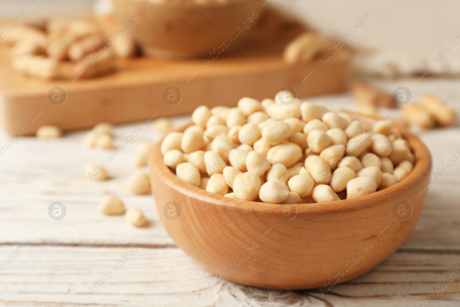 Photo of Shelled peanuts in wooden bowl on table