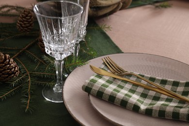 Photo of Christmas place setting with cutlery, glasses and festive decor on table, closeup