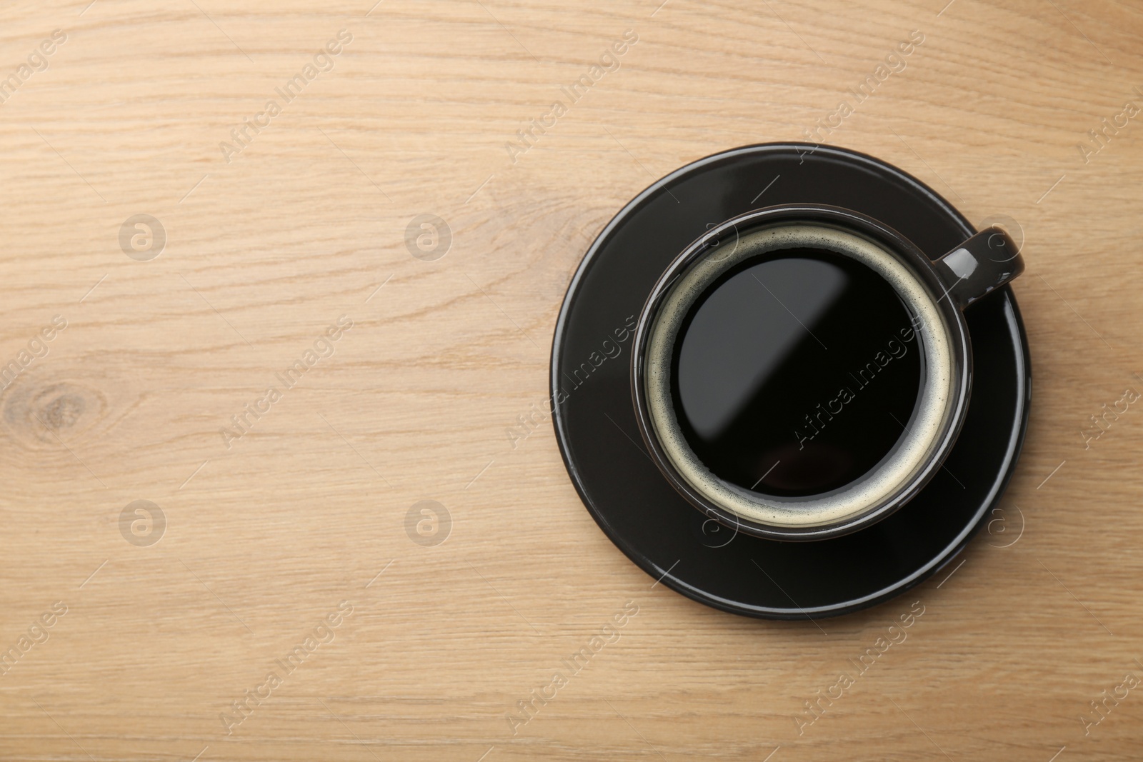 Photo of Hot coffee in cup on wooden table, top view. Space for text