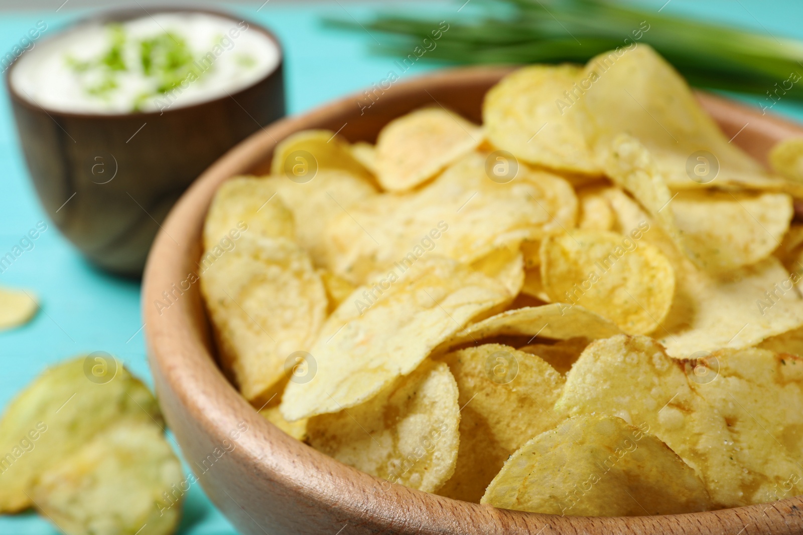 Photo of Sour cream and chips on blue wooden table, closeup