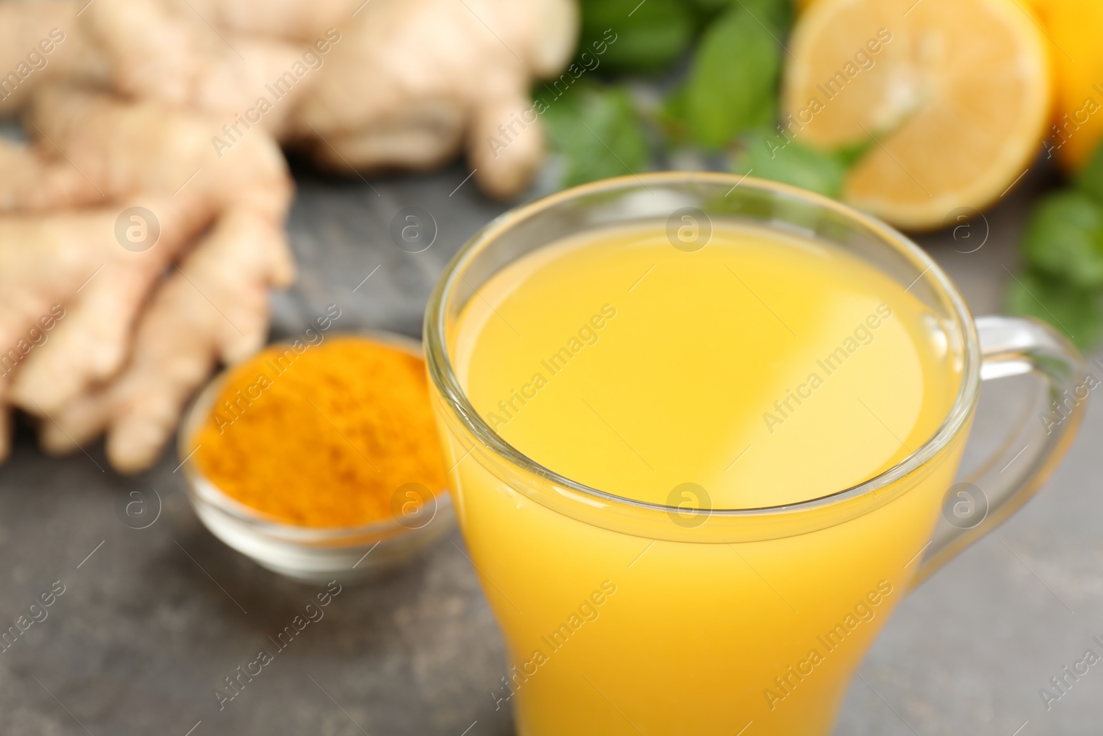 Photo of Immunity boosting drink and ingredients on grey table, closeup