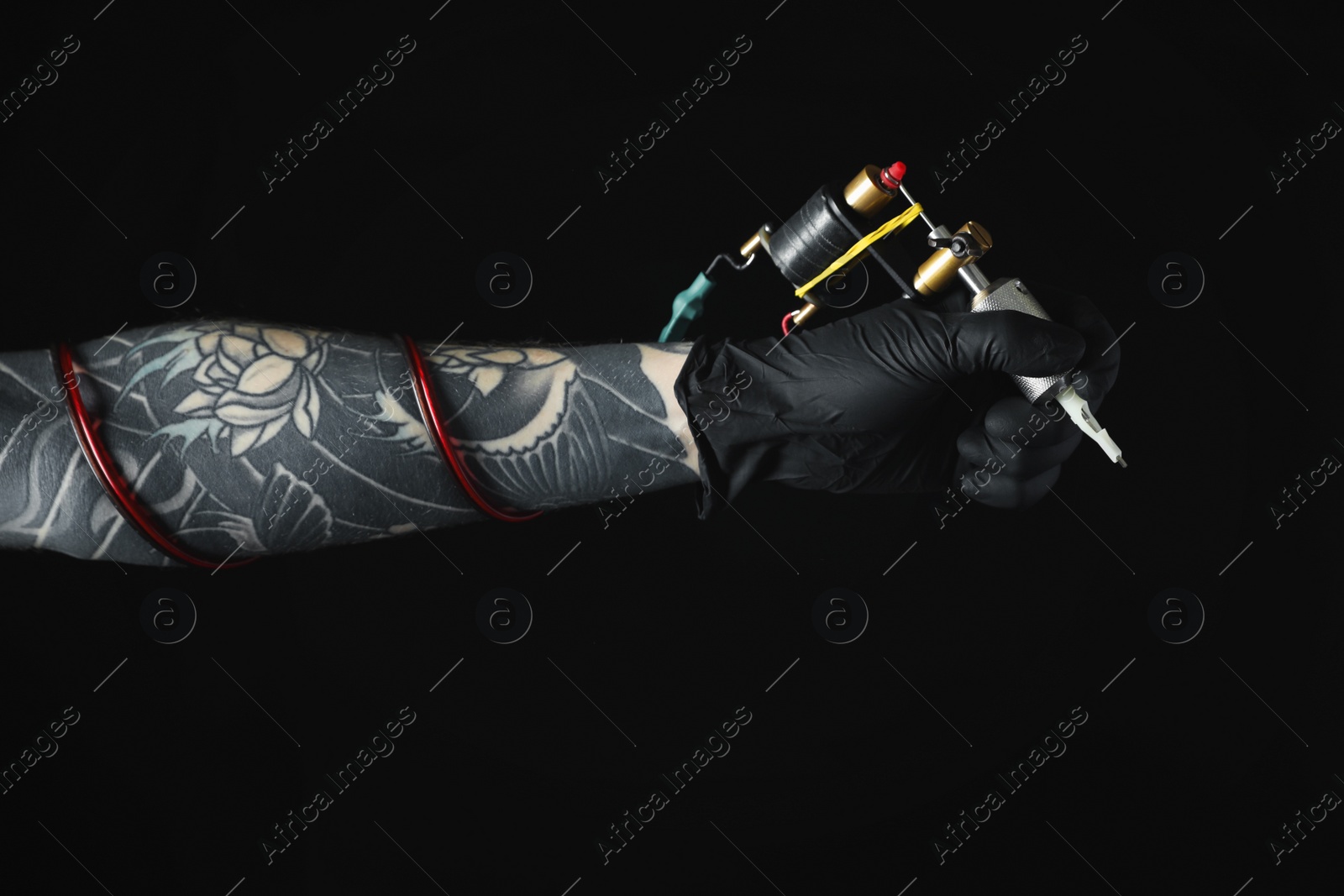 Photo of Tattoo artist with professional machine on black background, closeup