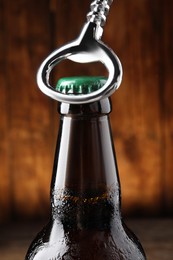 Opening bottle of beer on wooden background, closeup