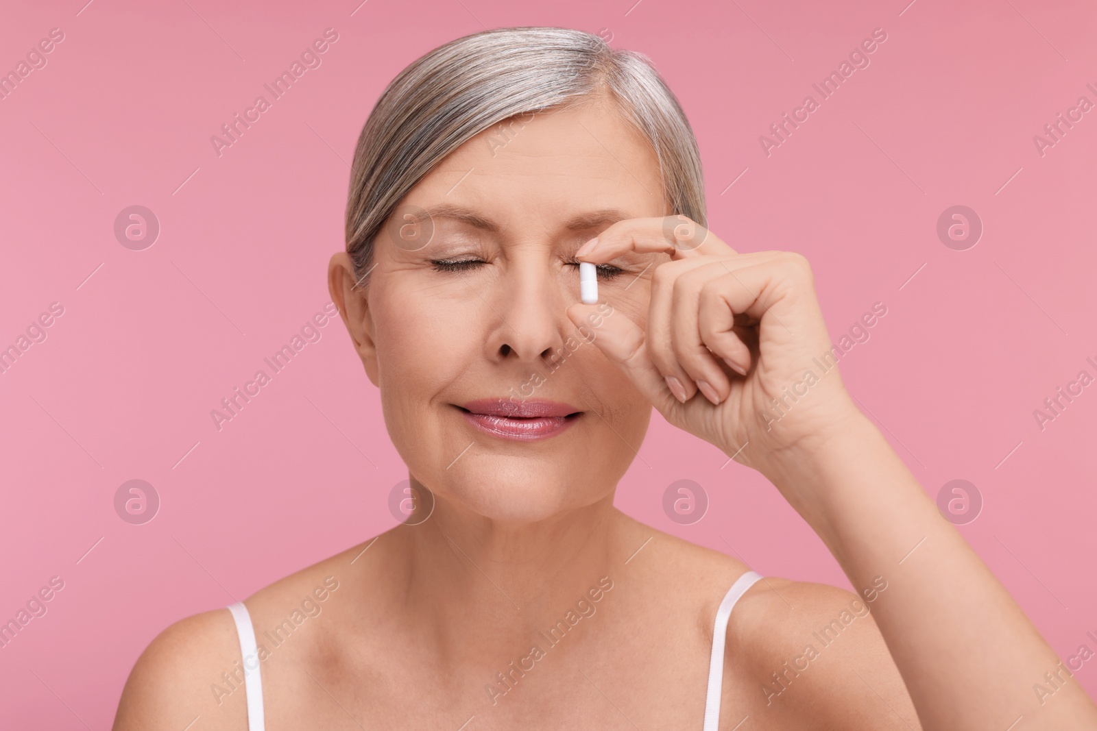 Photo of Beautiful woman with vitamin capsule on pink background