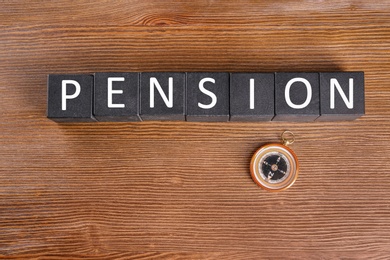 Cubes with space for text and compass on wooden background. Pension planning