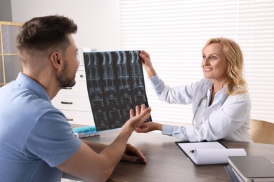 Photo of Doctor with MRI image consulting patient in clinic