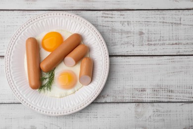 Photo of Delicious boiled sausages, fried eggs and dill on wooden table, top view. Space for text