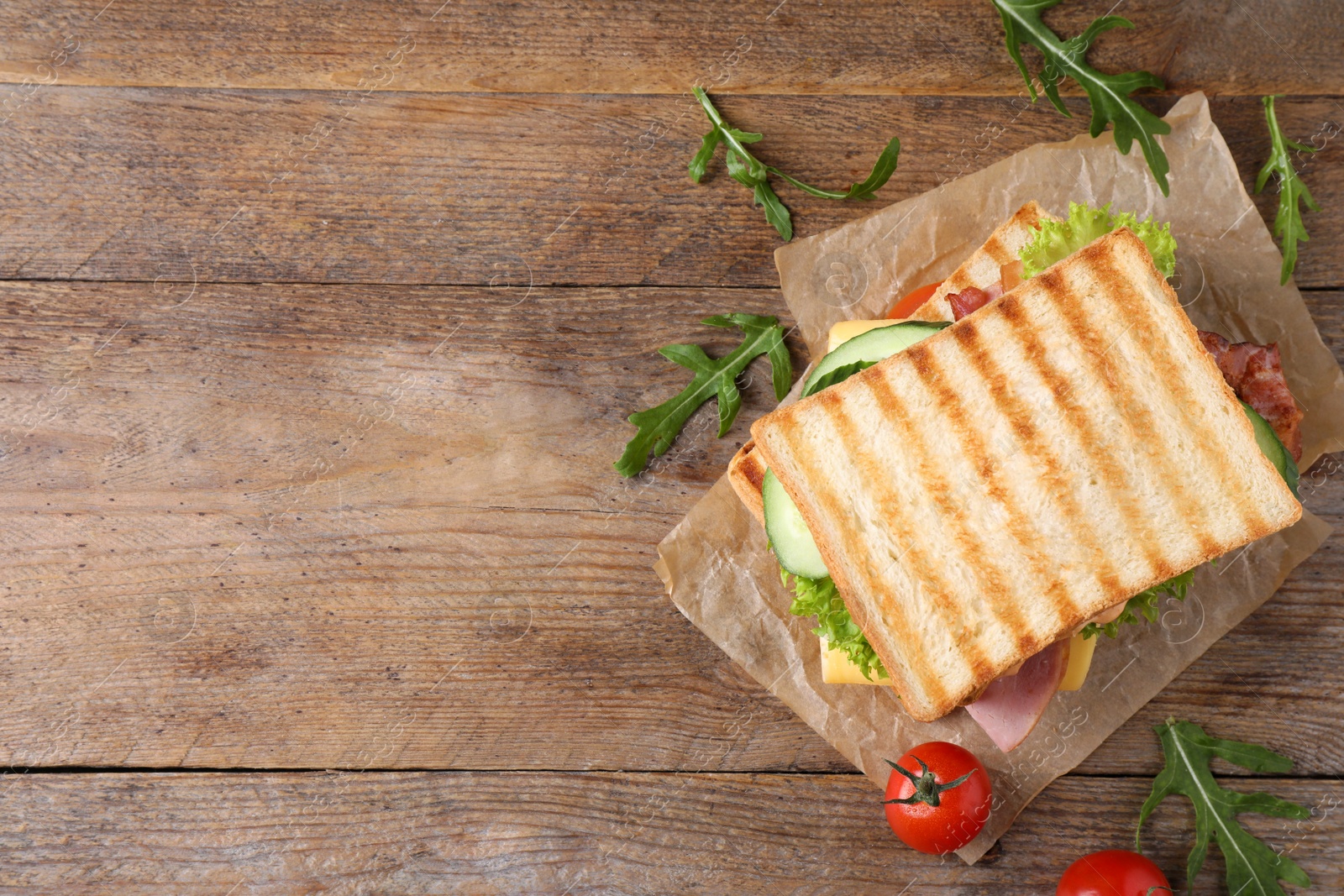 Photo of Tasty sandwich with  toasted bread on wooden table, top view. Space for text