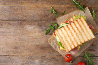 Photo of Tasty sandwich with  toasted bread on wooden table, top view. Space for text