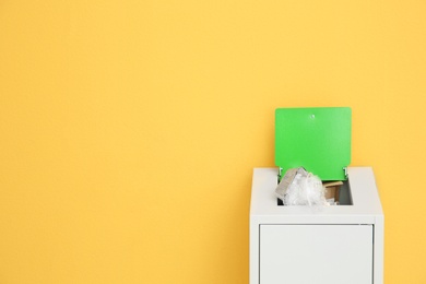 Photo of Overfilled trash bin on color background, space for text. Recycling concept