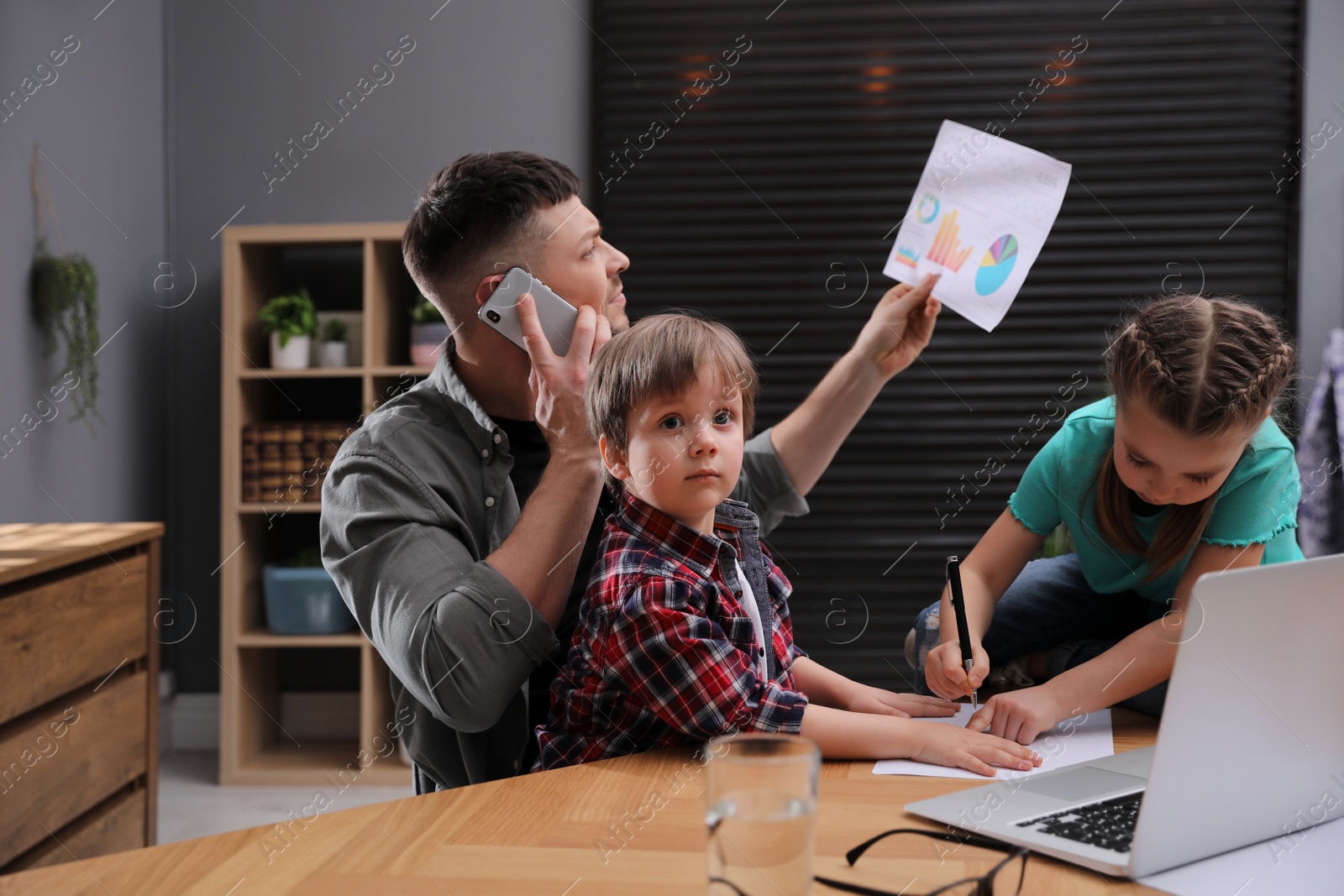 Photo of Overwhelmed man combining parenting and work at home